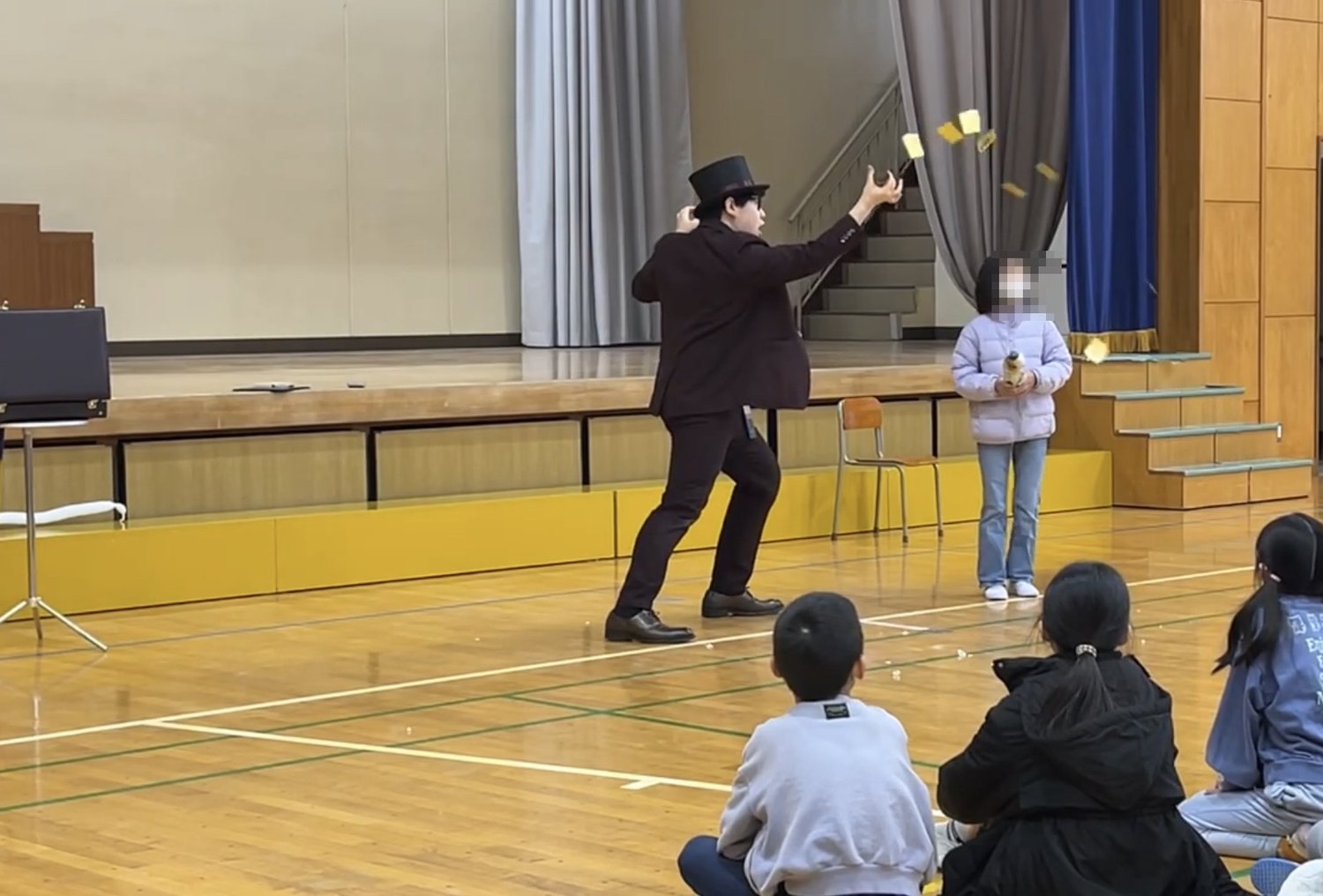 舞台の前で、児童のお客様に手伝ってもらいながらマジックを演じている様子