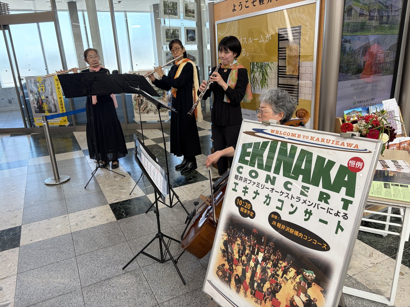 軽井沢駅の構内で演奏されているエキナカコンサートの様子と、コンサートの案内看板