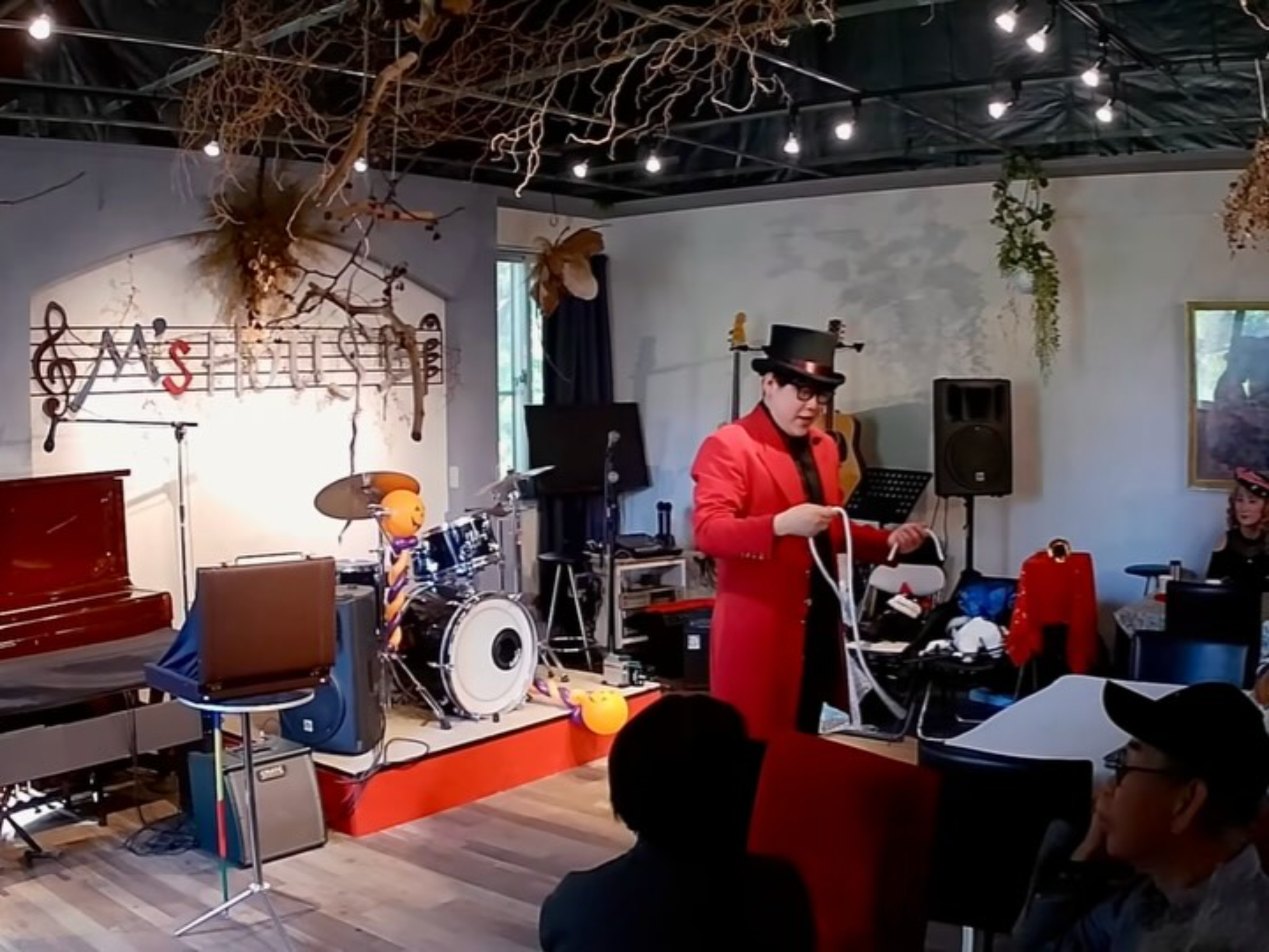M's Houseのステージで、ロープを使ったマジックを披露するDaiSukeと、それを見守るお客様の後ろ姿