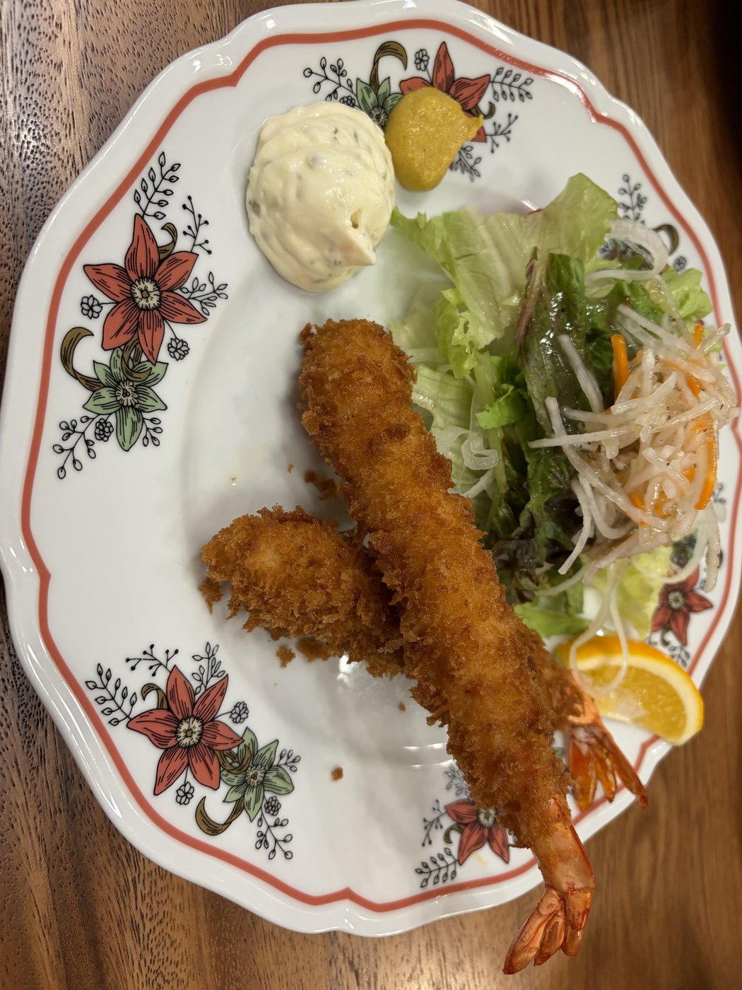 花柄のお皿に盛られた大きな海老の揚げ物とサラダ
