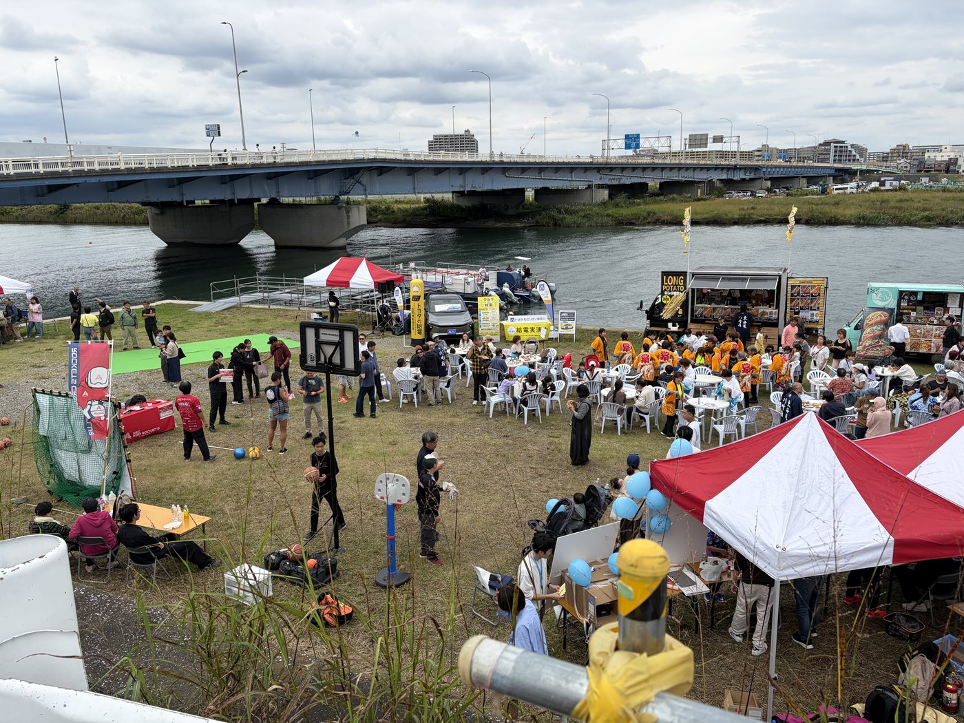 川沿いの広場に屋台やテントが並び、多くの人でにぎわう野外会場