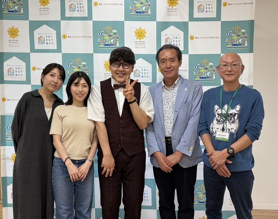 ロゴの並ぶパネルの前で、イベント関係者の皆さんとDaiSukeが並んだ記念写真